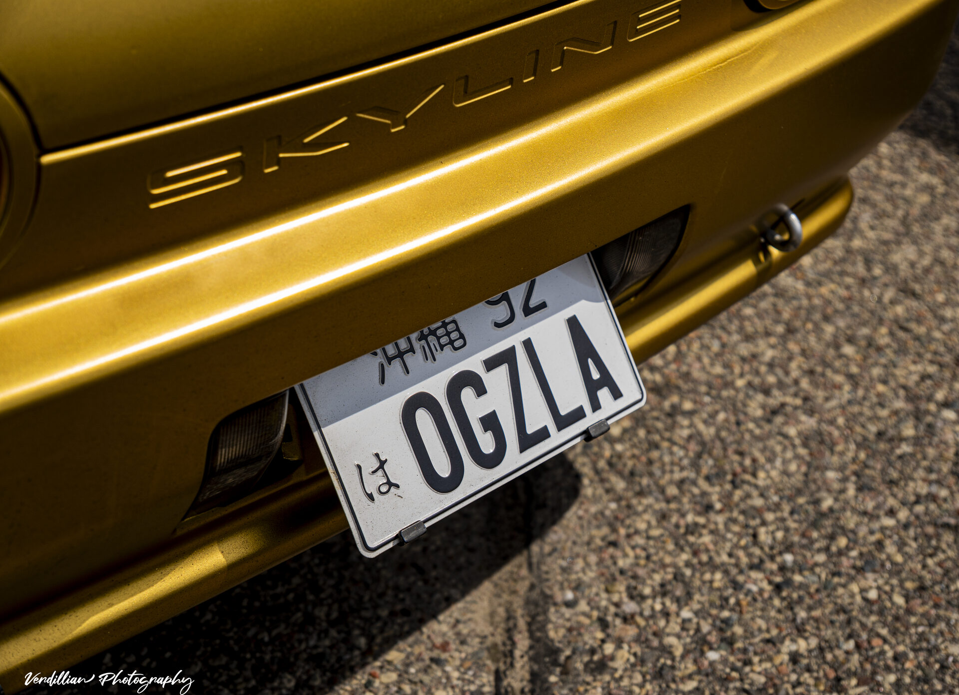 Rear badge and Japanese license plate on a gold Nissan Skyline